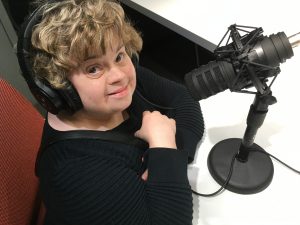 Woman at microphone, wearing headphones and smiling