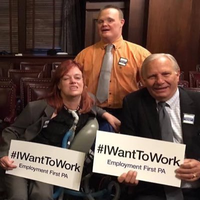 Three people, two of which have signs stating with the hashtag I want to work.